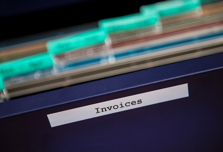 A blue filing cabinet with an 'invoices' label containing several files